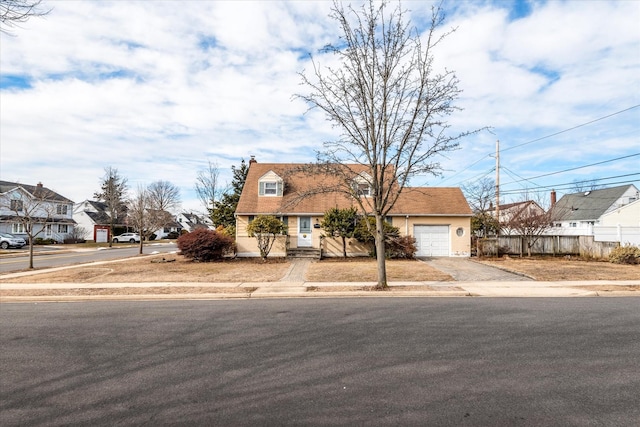 view of front of house with driveway, an attached garage, fence, and a residential view