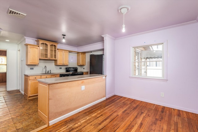 kitchen featuring light brown cabinets, a sink, visible vents, light countertops, and black appliances