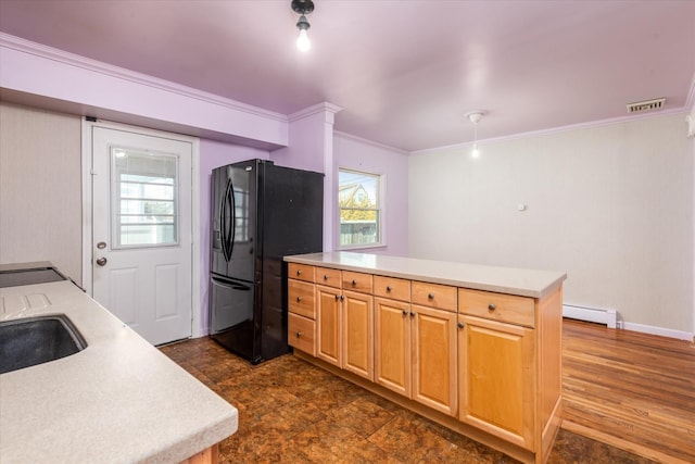 kitchen with visible vents, ornamental molding, baseboard heating, light countertops, and black fridge