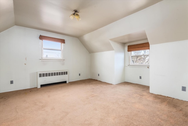 bonus room with vaulted ceiling, radiator heating unit, plenty of natural light, and light carpet