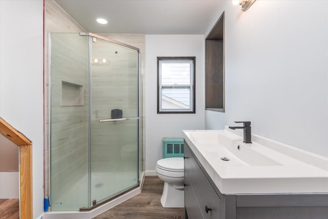 bathroom with toilet, wood finished floors, visible vents, vanity, and a shower stall