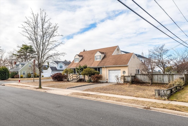 view of front of home with driveway, an attached garage, fence, and a residential view