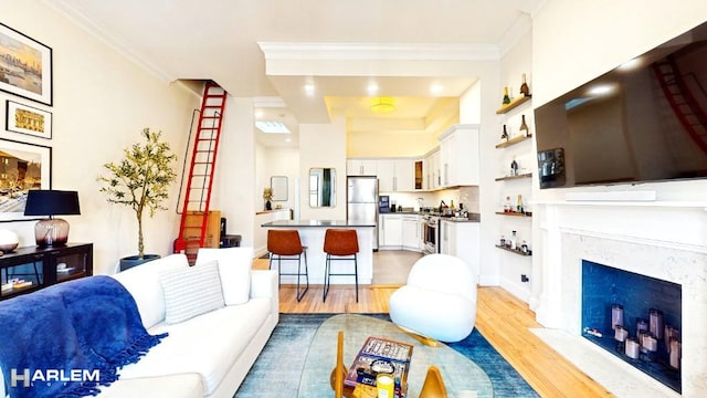 living area with light wood-style flooring, a fireplace, and ornamental molding