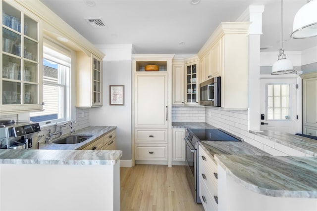 kitchen featuring sink, hanging light fixtures, light wood-type flooring, stainless steel appliances, and backsplash