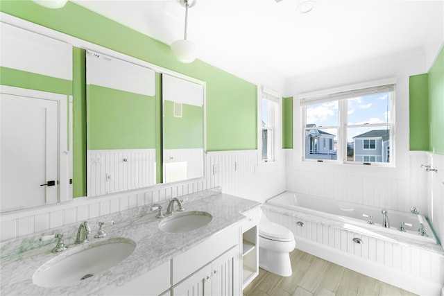 bathroom featuring vanity, a bath, and toilet