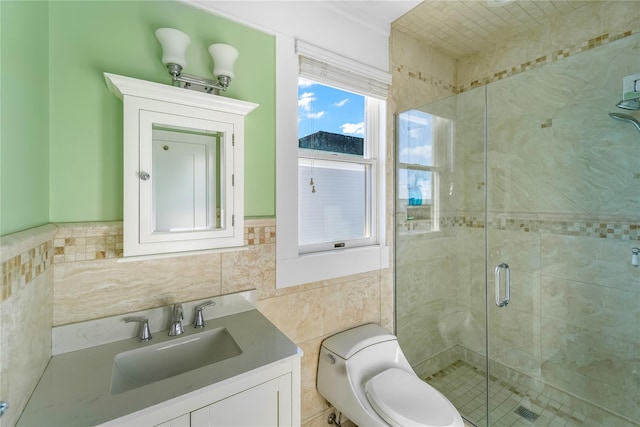 bathroom with a shower with door, vanity, tile walls, and toilet