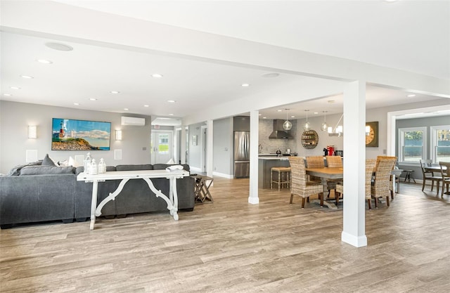 living room with a wall mounted air conditioner and light hardwood / wood-style floors