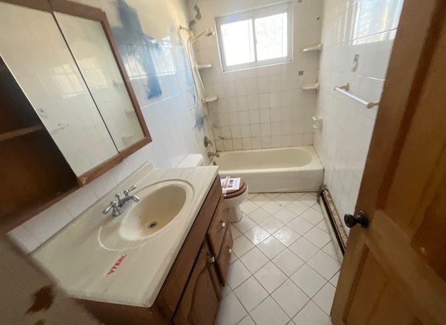 full bathroom with toilet, tiled shower / bath, tile walls, vanity, and tile patterned flooring