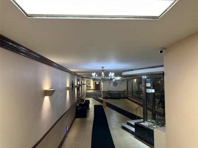 hall featuring dark hardwood / wood-style flooring, crown molding, and a chandelier