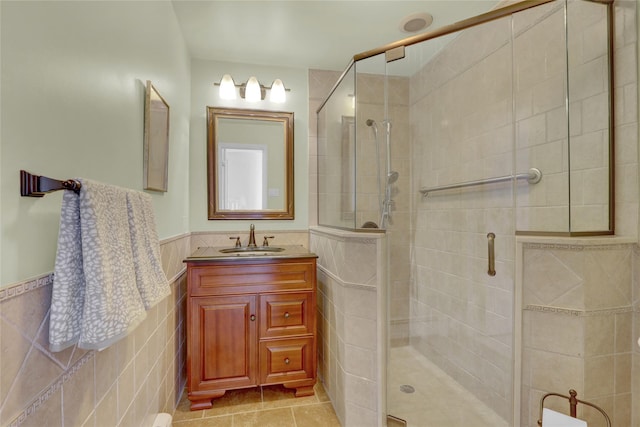 bathroom featuring vanity, tile walls, tile patterned floors, and a shower with shower door