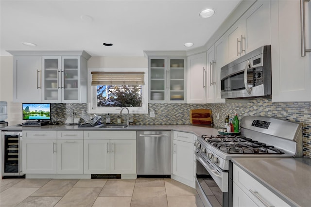 kitchen featuring wine cooler, sink, white cabinetry, and appliances with stainless steel finishes