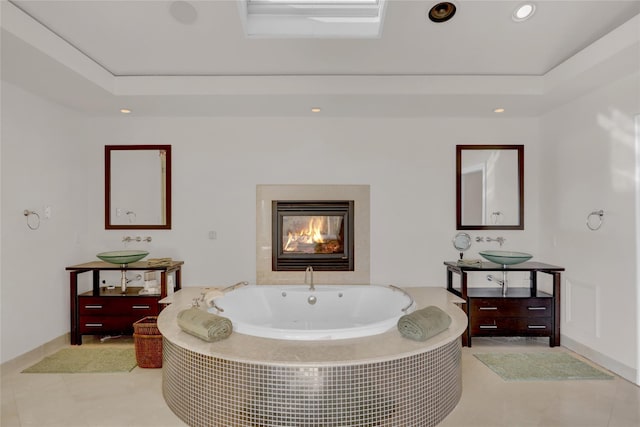 bathroom with vanity, a tray ceiling, tile patterned floors, and tiled bath