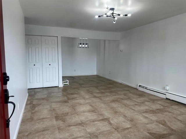 empty room featuring a chandelier and baseboard heating