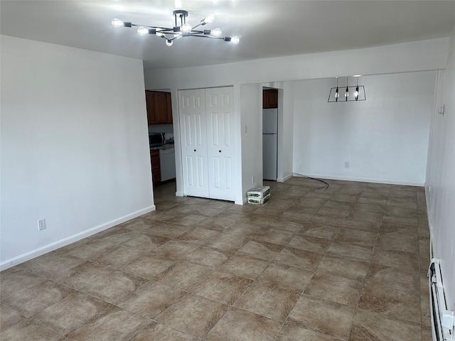 empty room with baseboard heating and a chandelier