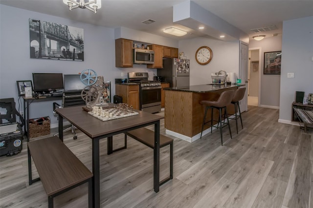 kitchen featuring sink, stainless steel appliances, a kitchen breakfast bar, and light hardwood / wood-style floors