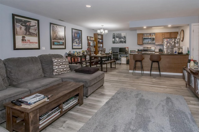 living room featuring a notable chandelier and light wood-type flooring