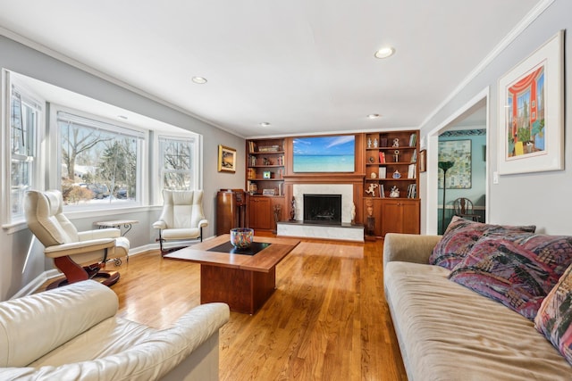 living room with hardwood / wood-style floors, crown molding, a fireplace, and built in features