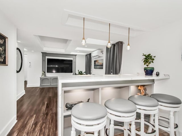 kitchen with a wall mounted AC, a breakfast bar area, baseboards, dark wood finished floors, and a peninsula