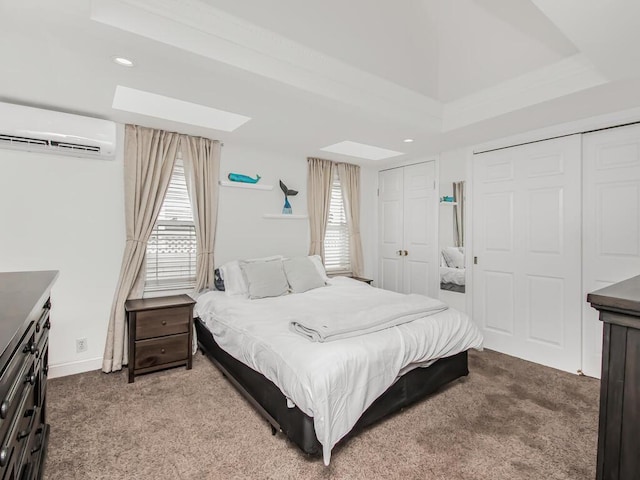 carpeted bedroom featuring a wall unit AC, multiple windows, two closets, and a raised ceiling