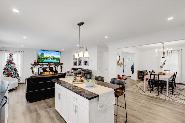 kitchen with hanging light fixtures, a center island, a breakfast bar area, and white cabinets