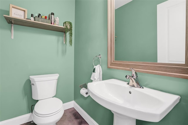 bathroom featuring parquet flooring, toilet, and sink