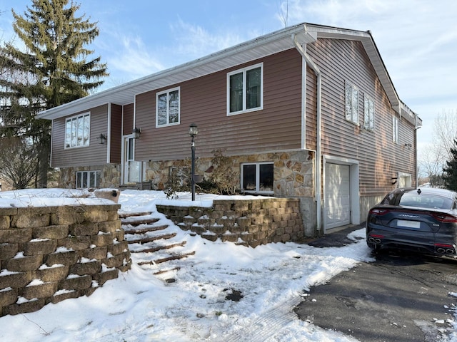 split foyer home featuring an attached garage and stone siding