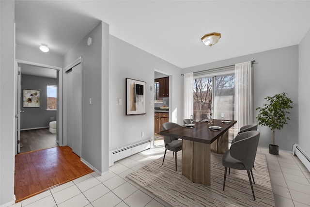 tiled dining room with a healthy amount of sunlight and a baseboard heating unit