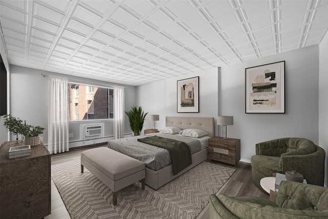 bedroom featuring a wall mounted air conditioner, a baseboard heating unit, and hardwood / wood-style floors