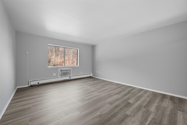 unfurnished room featuring a baseboard heating unit, hardwood / wood-style flooring, and an AC wall unit