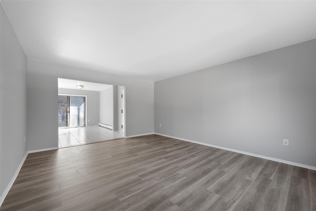 unfurnished room with hardwood / wood-style flooring and baseboard heating