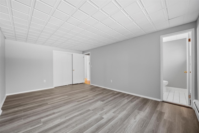 empty room featuring a baseboard heating unit and light hardwood / wood-style flooring