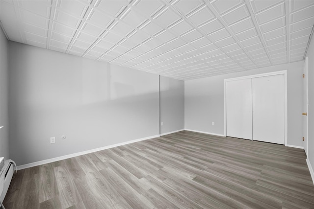 interior space with wood-type flooring and a baseboard heating unit