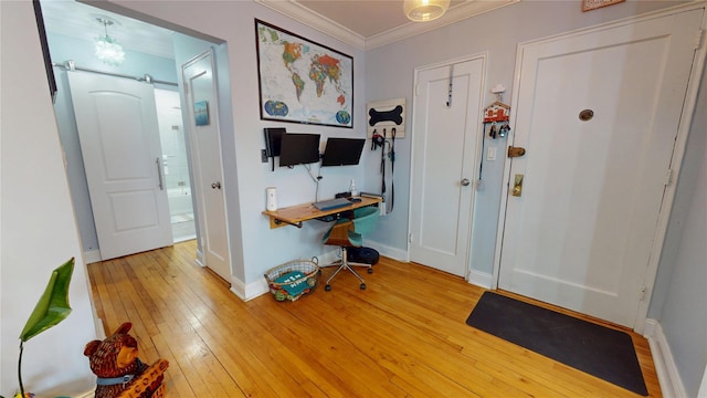 entryway with ornamental molding, a barn door, and light hardwood / wood-style flooring