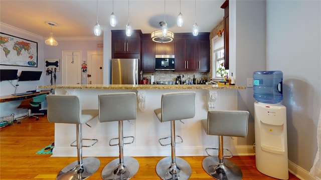 kitchen featuring stainless steel appliances, a kitchen bar, light hardwood / wood-style floors, and decorative backsplash