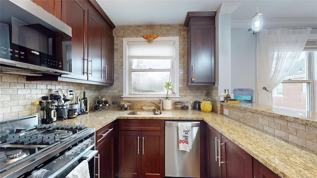 kitchen with pendant lighting, sink, appliances with stainless steel finishes, light stone countertops, and decorative backsplash