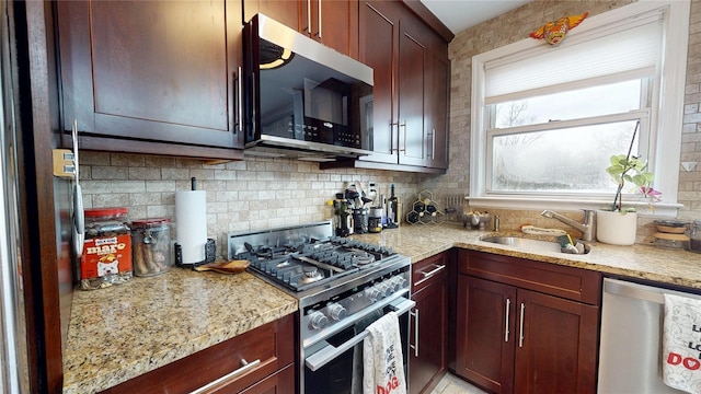 kitchen with light stone countertops, appliances with stainless steel finishes, sink, and decorative backsplash