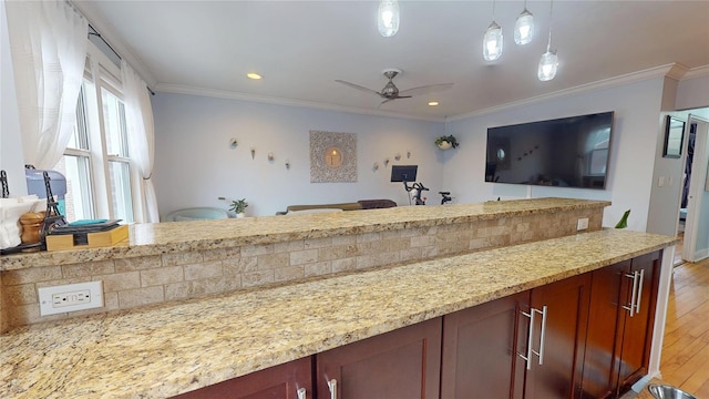 kitchen featuring pendant lighting, ceiling fan, light stone countertops, ornamental molding, and light hardwood / wood-style floors