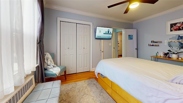 bedroom with ornamental molding, wood-type flooring, a closet, and radiator heating unit