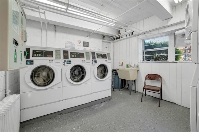 laundry area featuring radiator heating unit, washer and clothes dryer, and sink