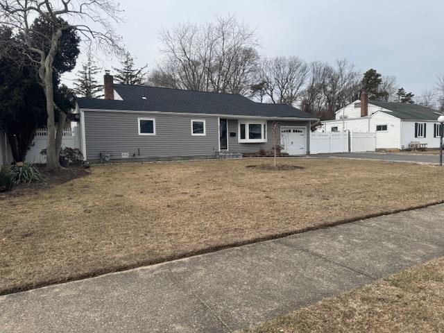 ranch-style house featuring a garage and a front lawn