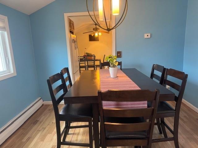 dining area with lofted ceiling, a baseboard heating unit, and hardwood / wood-style floors