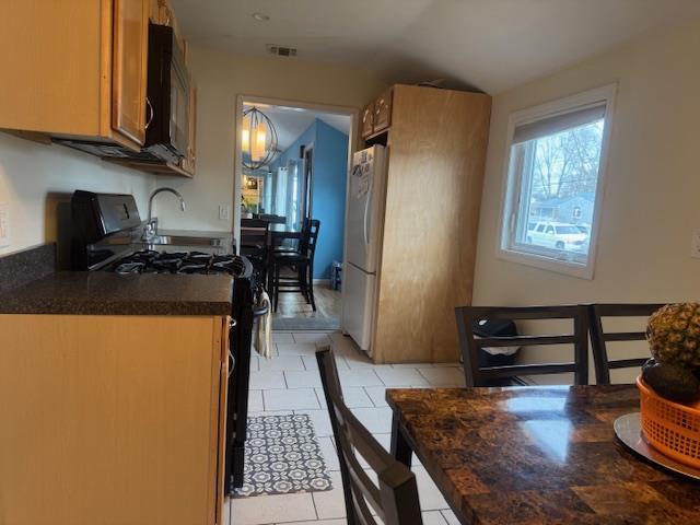 kitchen with plenty of natural light, light tile patterned floors, and black appliances