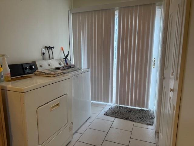 clothes washing area featuring light tile patterned floors and washer and dryer