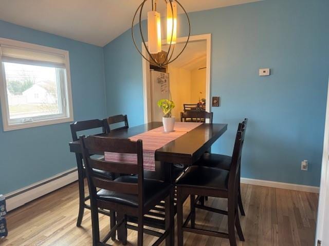 dining space with an inviting chandelier, hardwood / wood-style floors, and baseboard heating