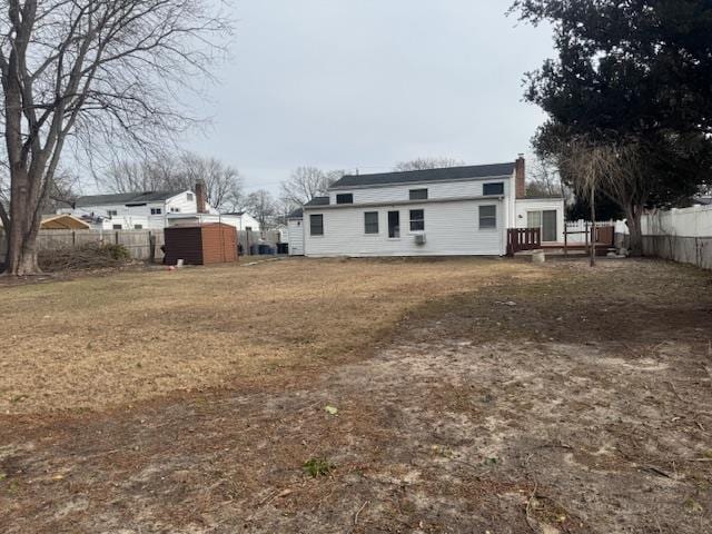 rear view of house featuring a wooden deck and a lawn