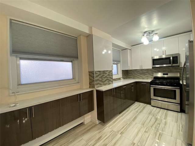 kitchen with white cabinetry, appliances with stainless steel finishes, dark brown cabinets, and backsplash