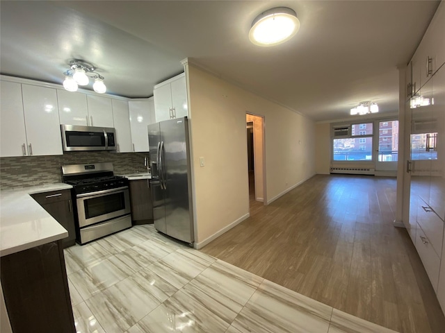 kitchen with tasteful backsplash, baseboard heating, appliances with stainless steel finishes, light hardwood / wood-style floors, and white cabinets