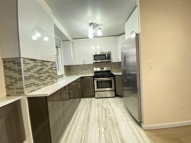 kitchen with white cabinetry, dark brown cabinetry, appliances with stainless steel finishes, and decorative backsplash