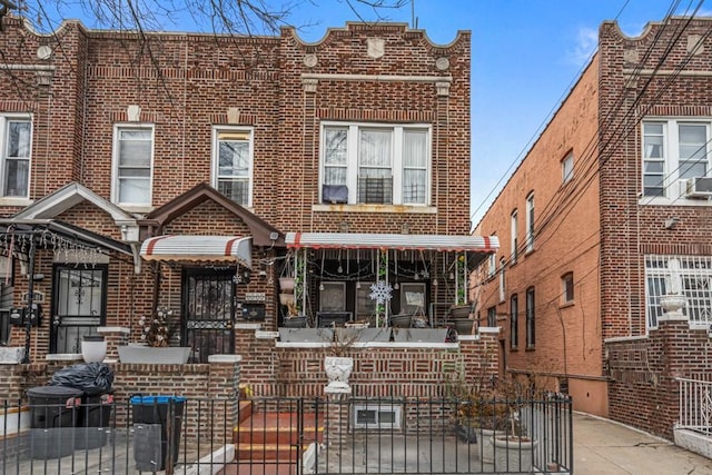 view of property with a fenced front yard, a gate, brick siding, and covered porch