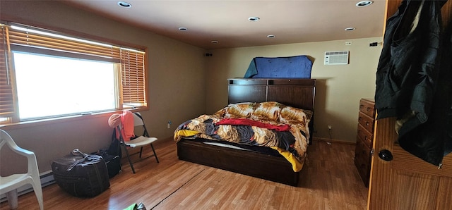 bedroom with wood-type flooring and an AC wall unit